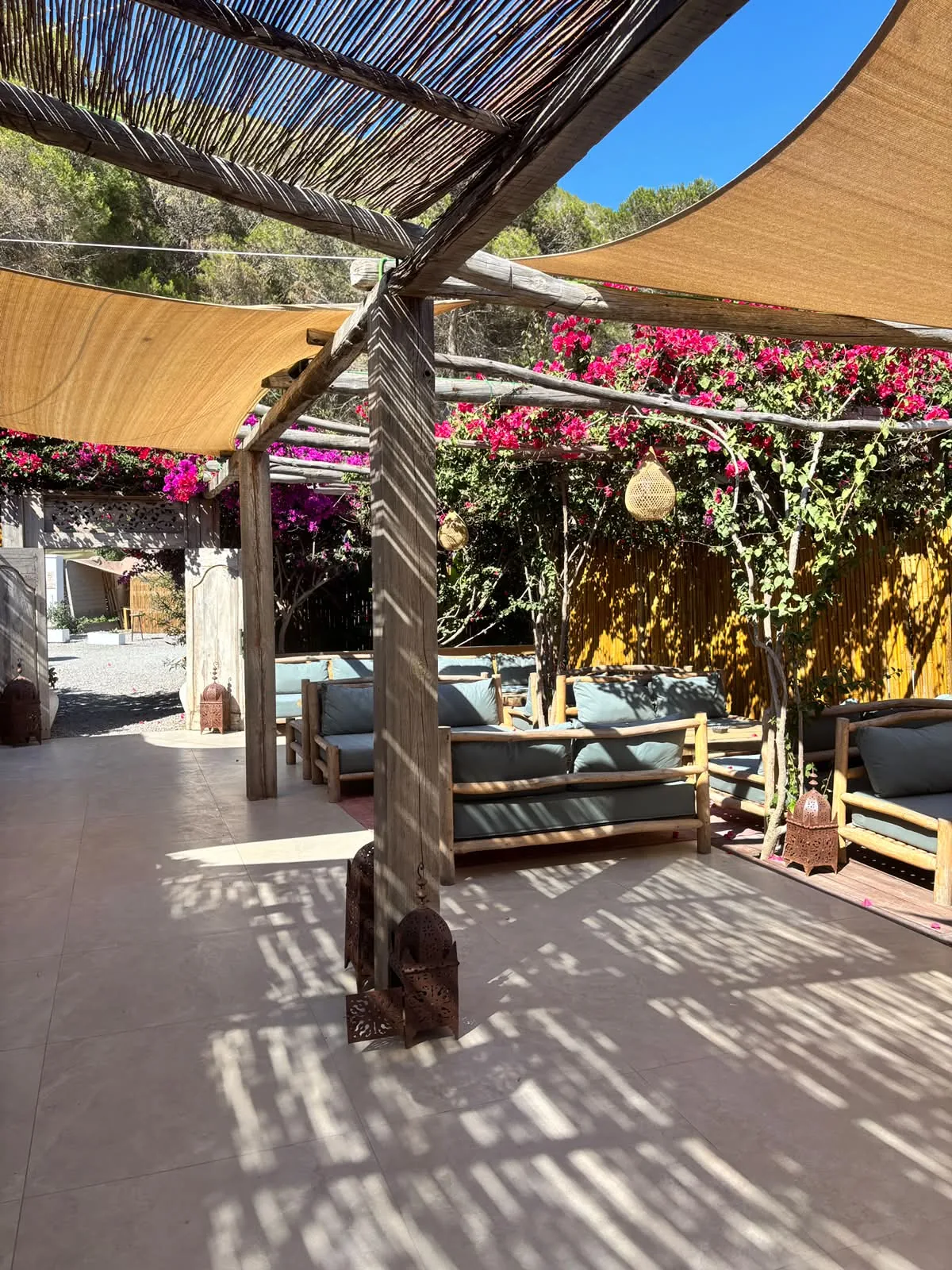 Area ristorante coperta di Elements Ibiza con tavoli in legno e vista sul verde