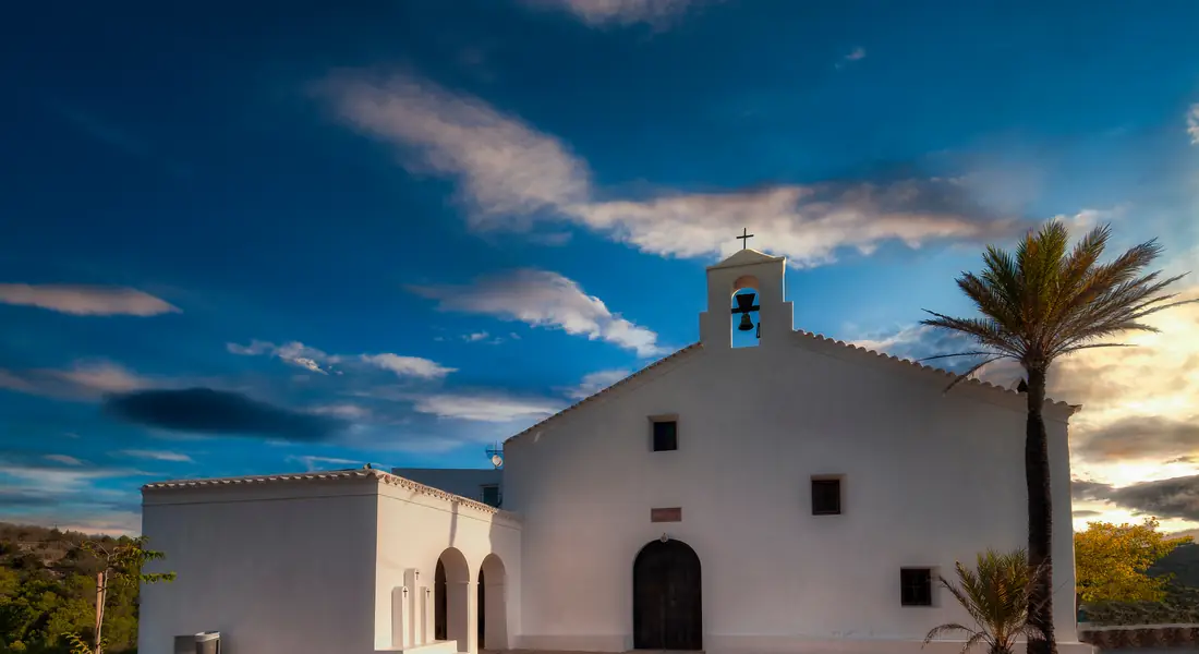Weiße Dorfkirche von Sant Vicent de sa Cala bei Sonnenuntergang