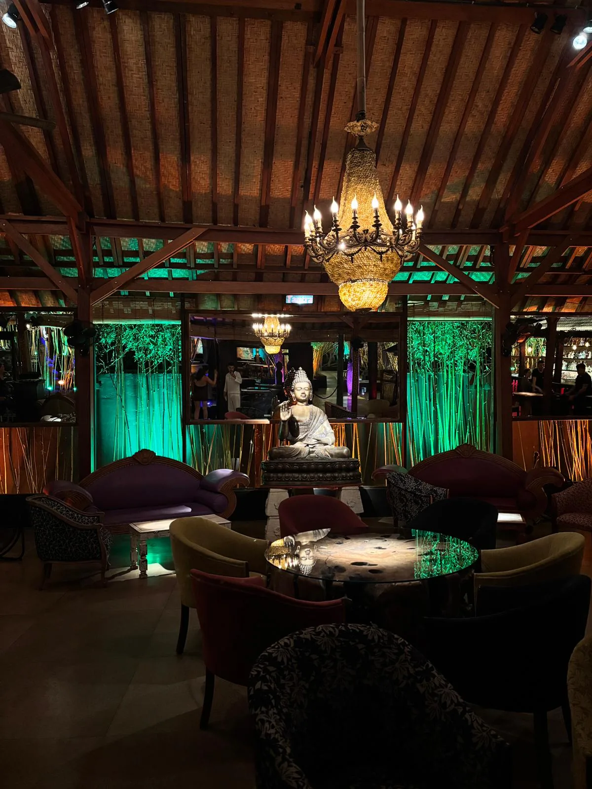 Lounge mit Buddha-Statue und grüner Beleuchtung im Bambuddha