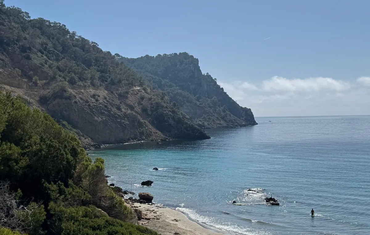 Sandstrand der Cala Boix vor bewaldeter Steilküste an der Ostküste Ibizas