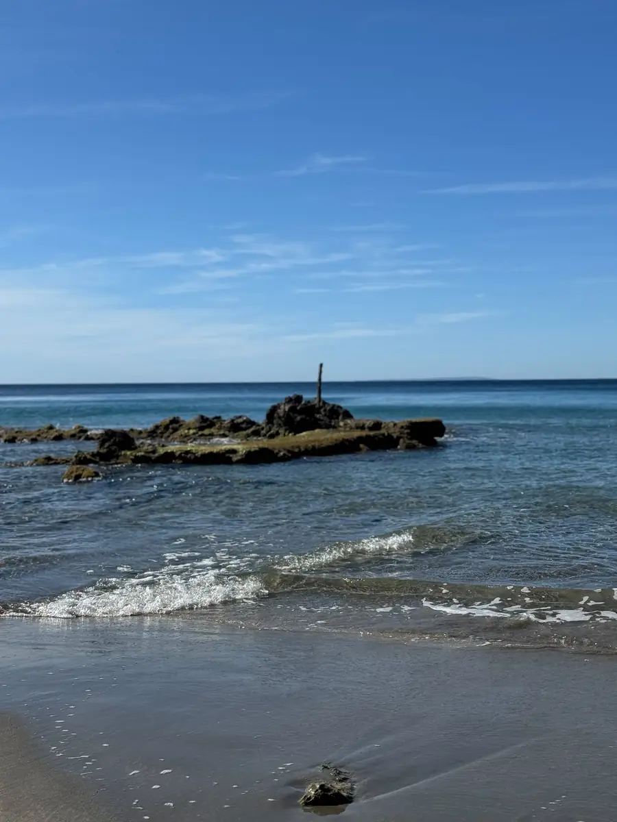 Vom Wasser umspülte dunkle Felsen in der klaren türkisblauen Bucht der Cala Boix