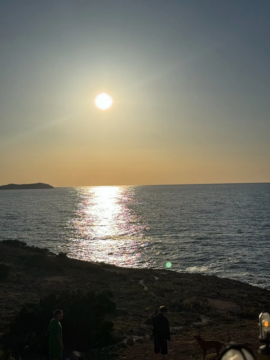 Orangeroter Sonnenuntergang mit Spiegelung auf dem Wasser bei der Cala Comte