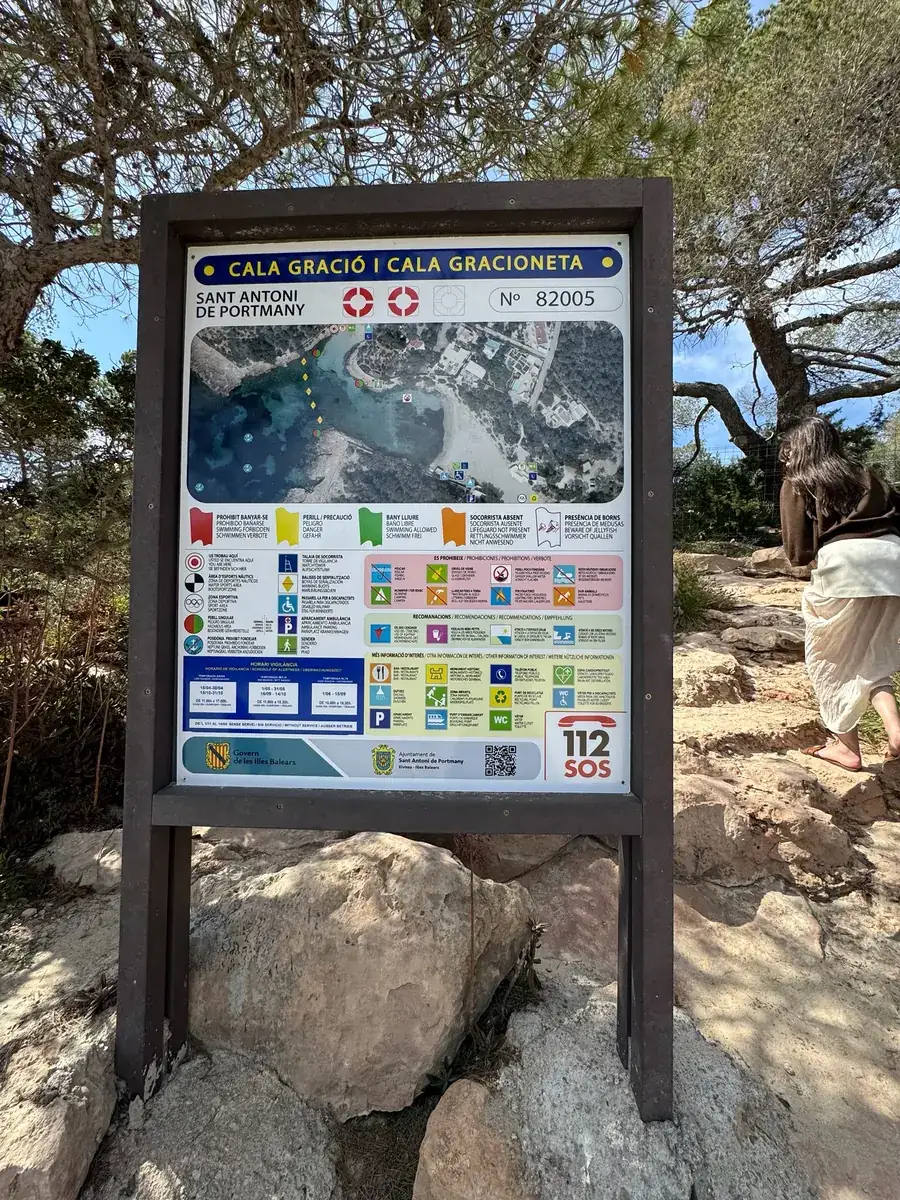 Informationstafel der Strandbehörde zu Cala Gració und Cala Gracioneta mit Bucht-Plan am Zugang