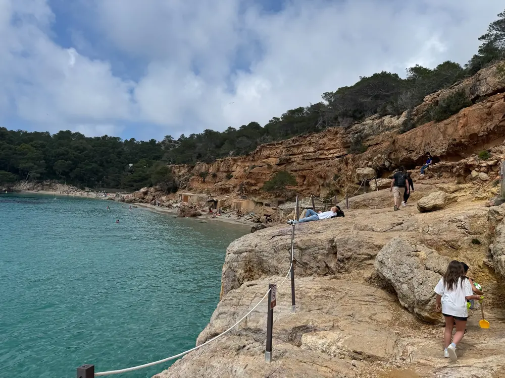Rocky coastal path along Cala Salada with views of the beach, fishermen’s huts and turquoise water