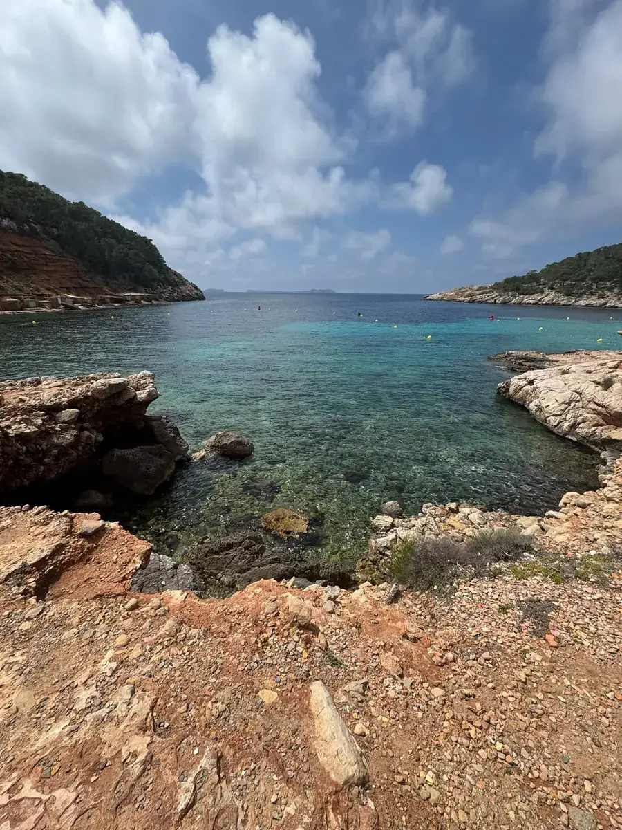 Crystal-clear water over rocks at the edge of Cala Salada with a view of the open sea