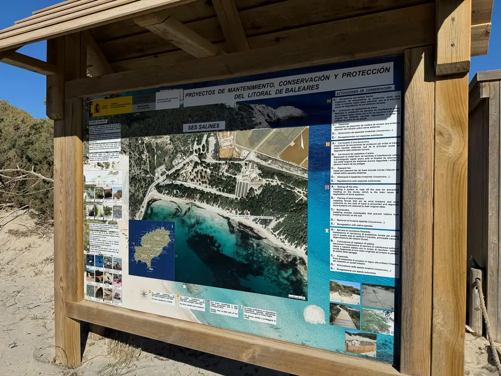 Information board on the beach at Ses Salines with aerial view of the bay and notes on protecting the dunes in the nature reserve