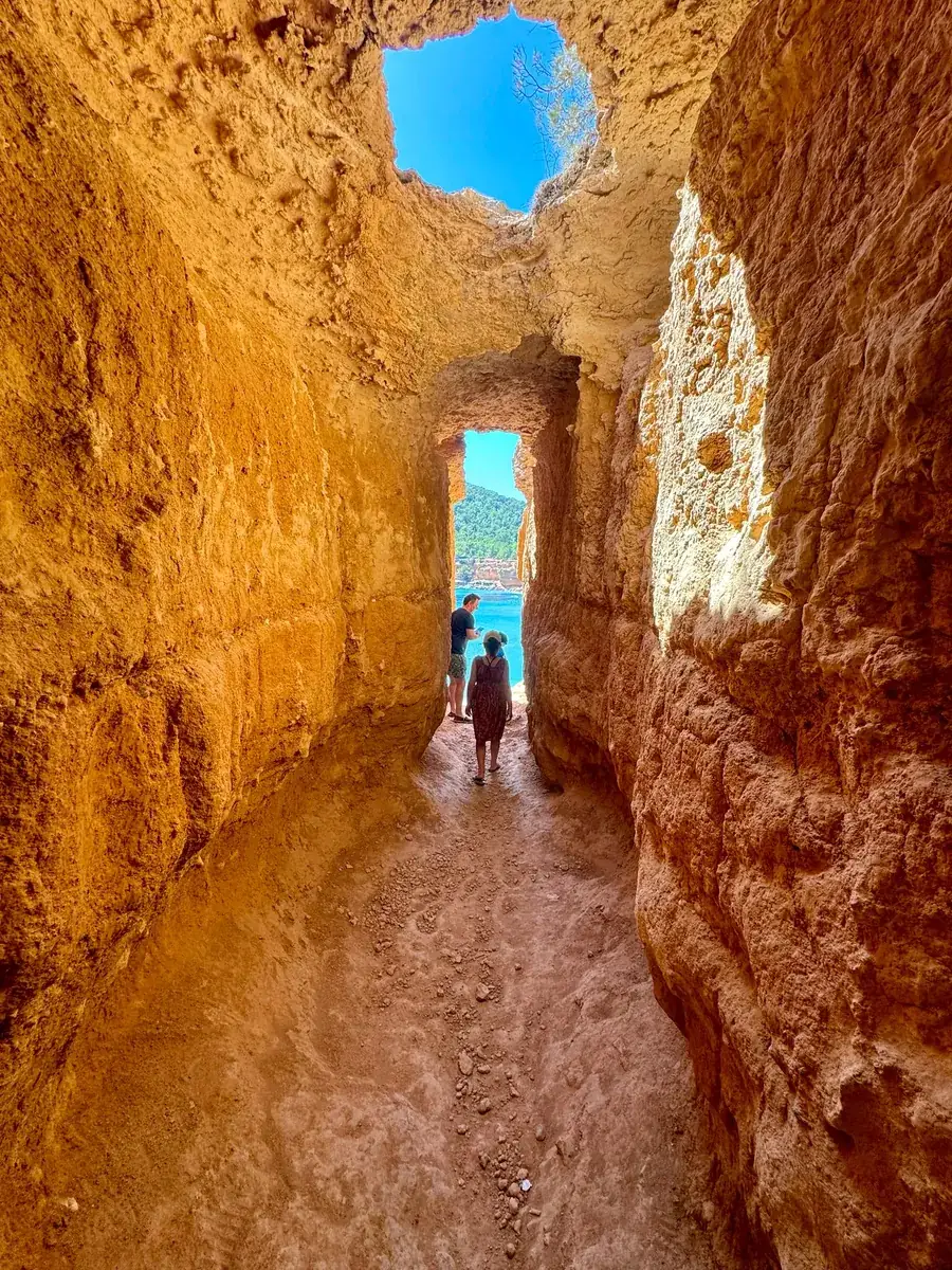 Passage étroit taillé dans le grès d’une grotte cachée près de Sa Caleta avec vue sur la mer turquoise