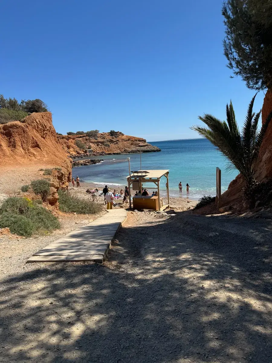 Passerelle en bois menant de l’accès jusqu’à la plage de Sa Caleta, avec la baie et la mer en arrière-plan